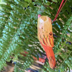 drewniany kolorowy ptaszek wiszący na tle paproci
