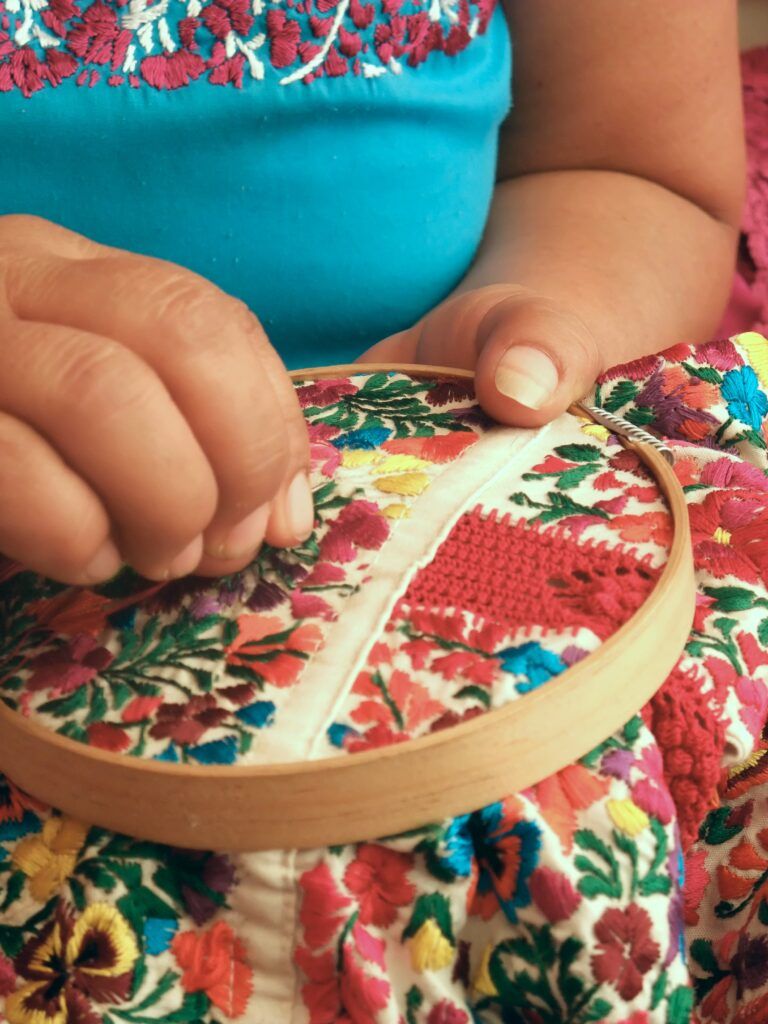 dłonie które wykonują wielobarwny haft