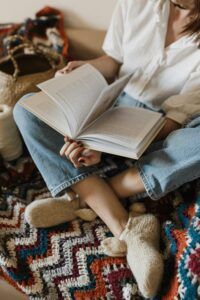 Person sitting comfortably while reading, surrounded by cozy knit and crochet items.